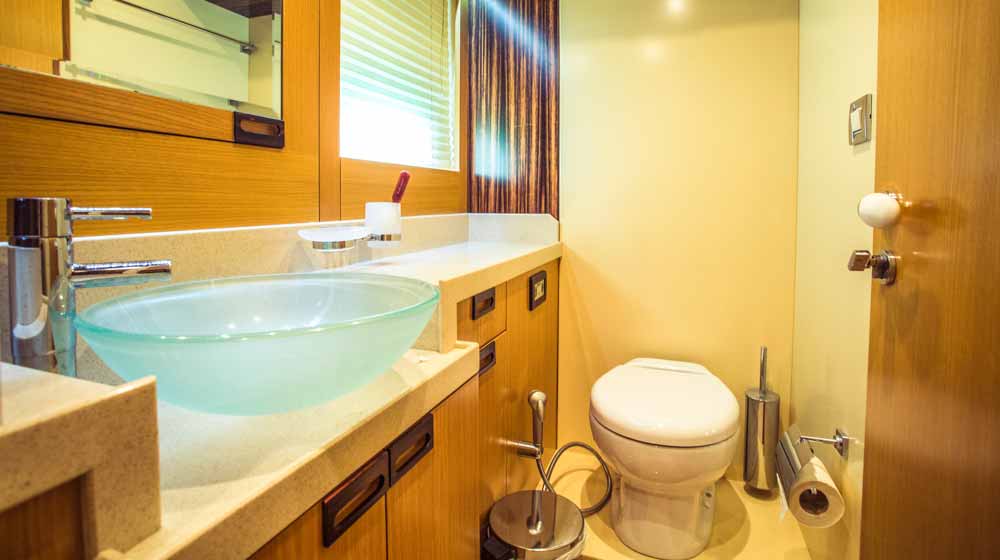 yacht washroom features a wood surrounded head, sink, side window